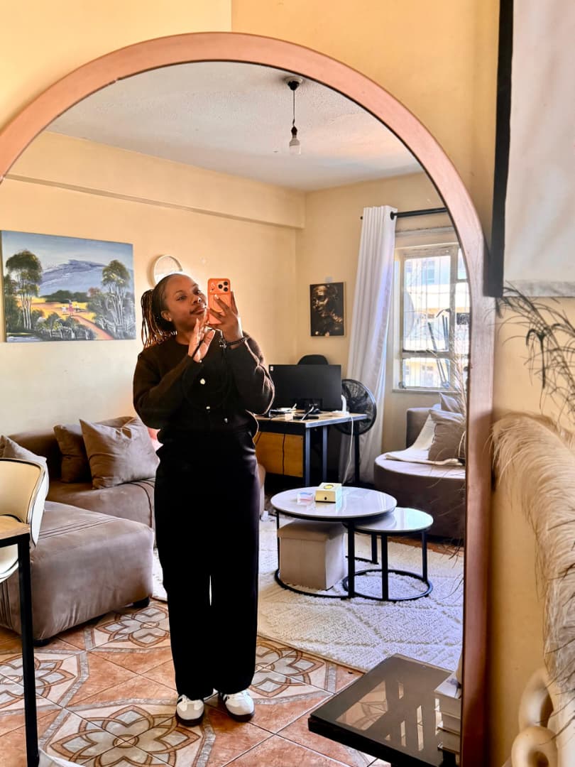 Natalie in an arched mirror, smiling in soft daylight